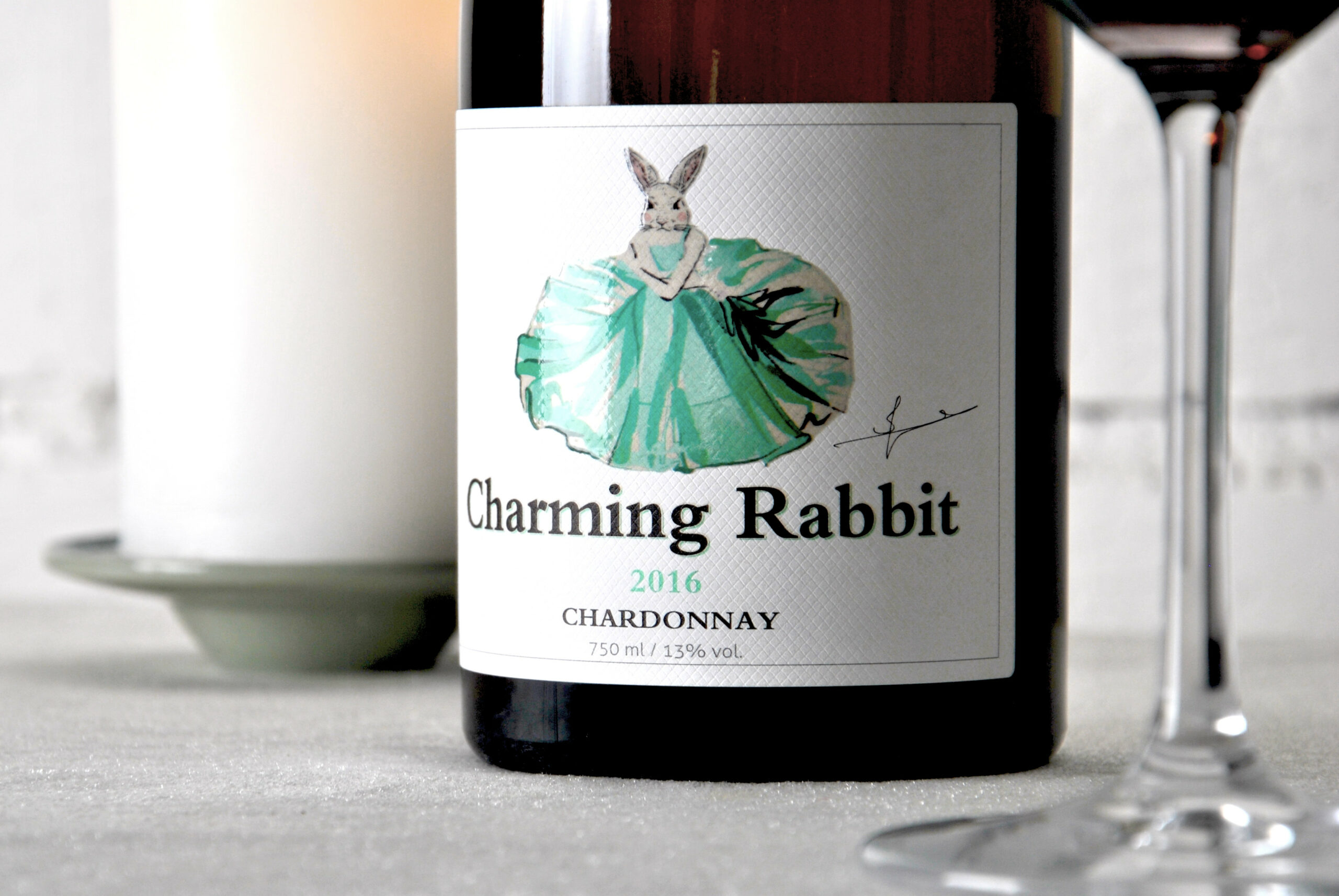 Close-up of a Charming Rabbit Chardonnay wine label beside glasses