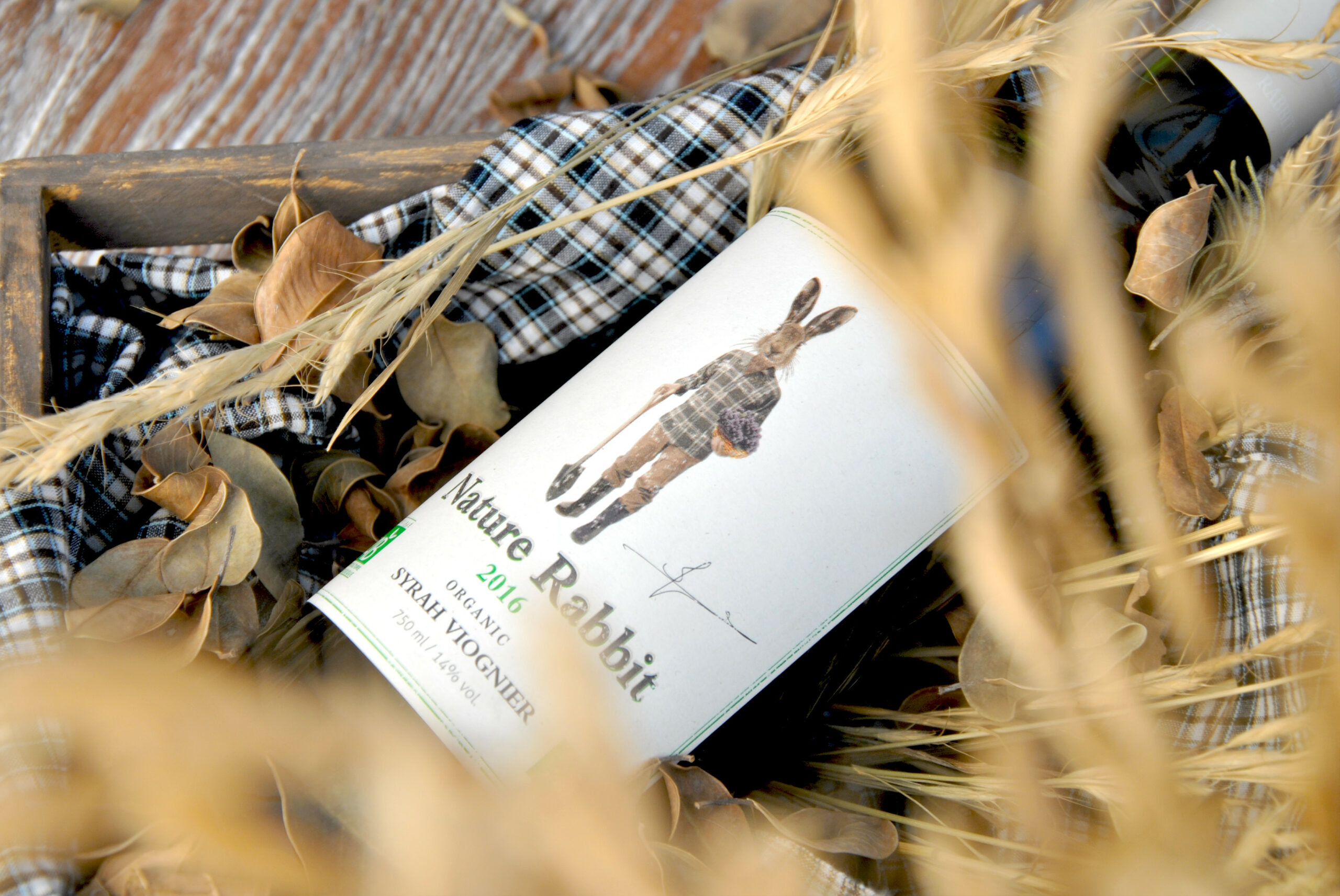 Nature Rabbit Syrah Viognier wine bottle nestled among straw and vine leaves