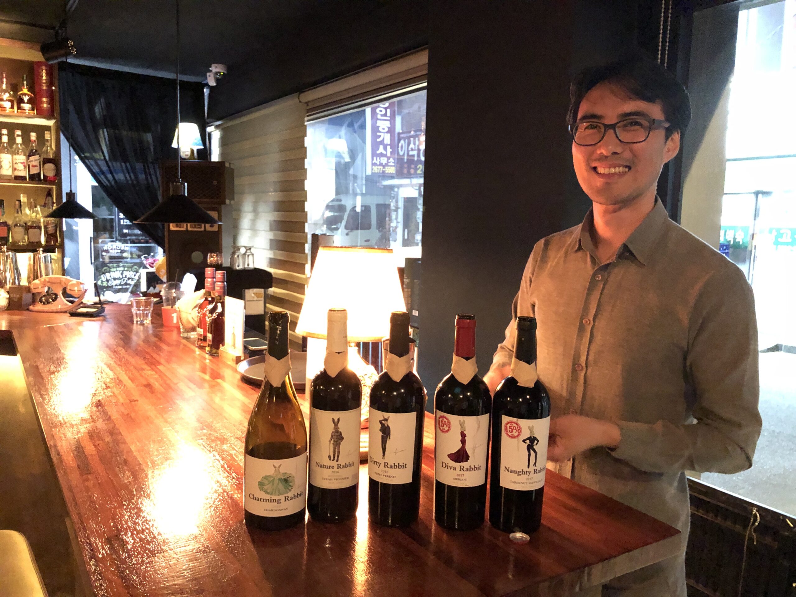 Sharing Rabbit Family wines A presenter with Rabbit Family wine bottles at a wooden bar.